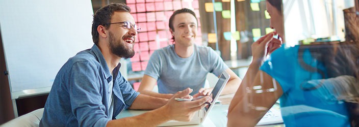 Three seated people smiling in conversation