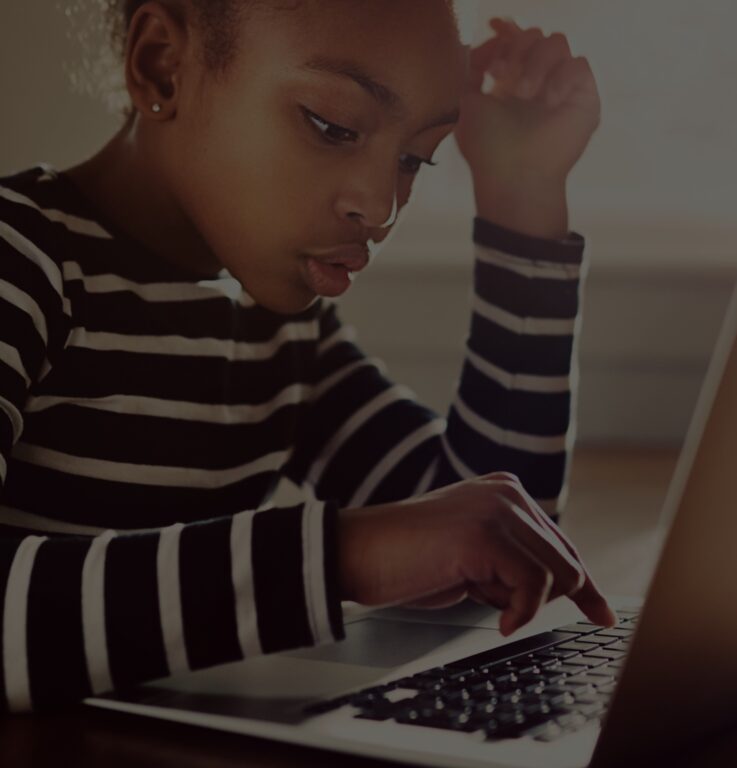 photo of a young girl typing on a laptop