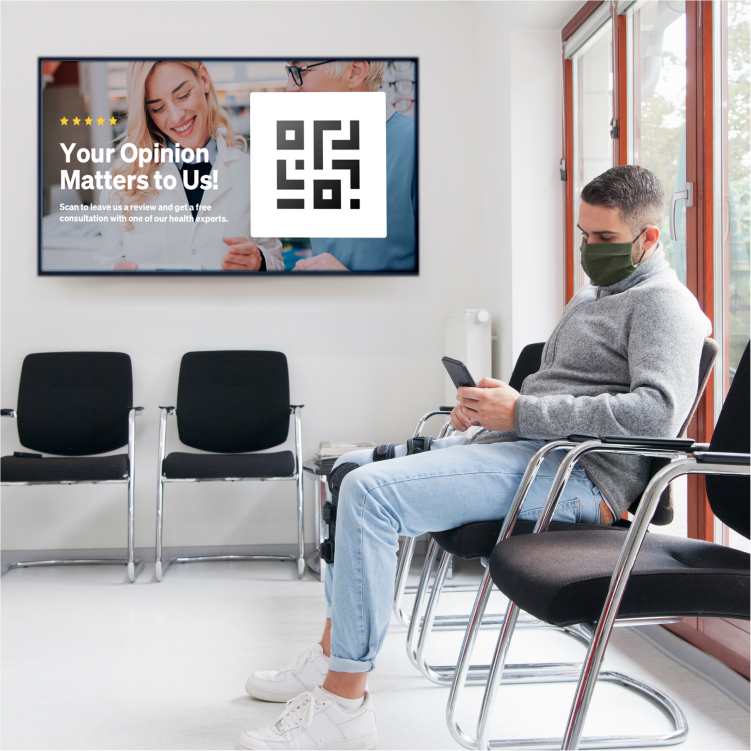 Man sits near UPshow digital signage in waiting room.