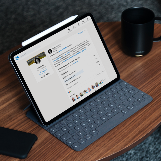 Tablet on a desk displaying Brooks Bell CEO's LinkedIn post next to a phone and mug