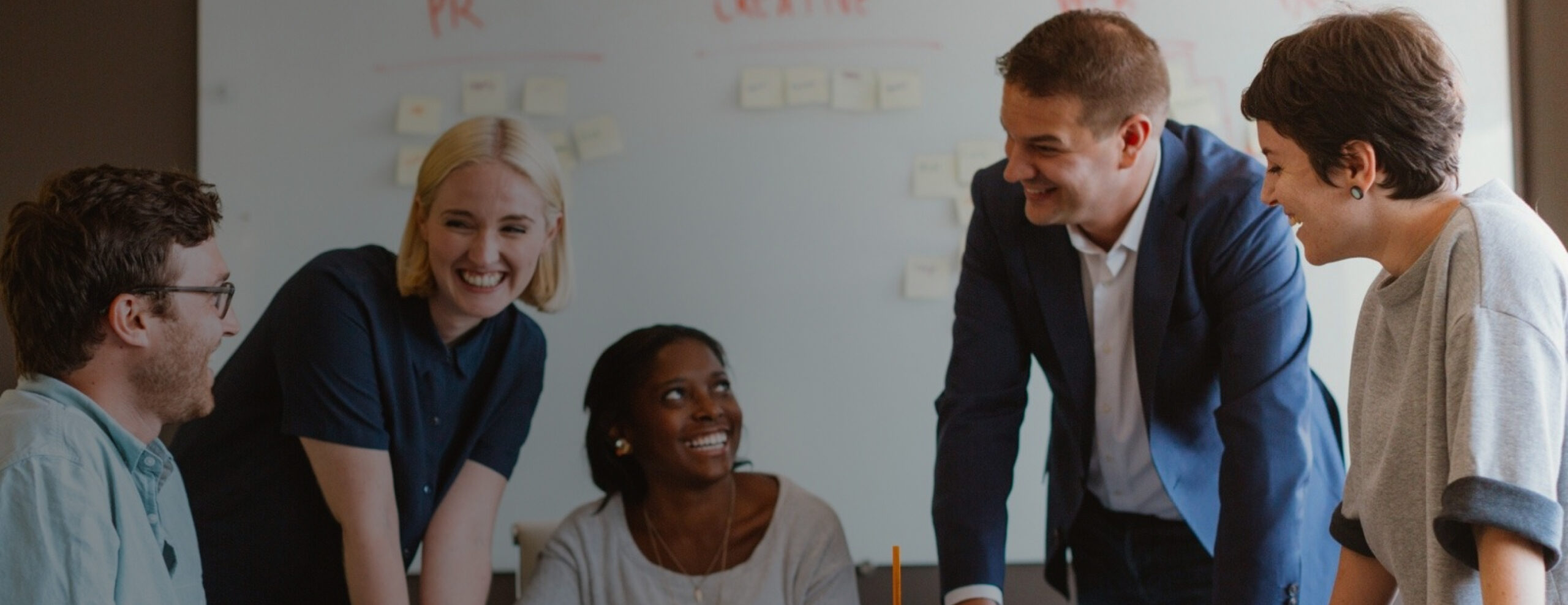 Group of five coworkers in a conference room smiling at each other