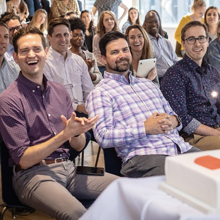 Three Walker Sands Employees clapping while watching a presentation