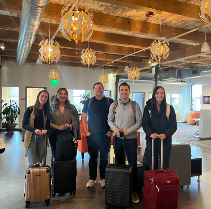 Five colleagues stand with their suitcases after arriving to an office in Boston