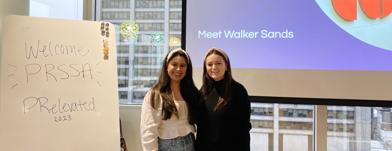 Two women smiling and standing in front of a projector screen