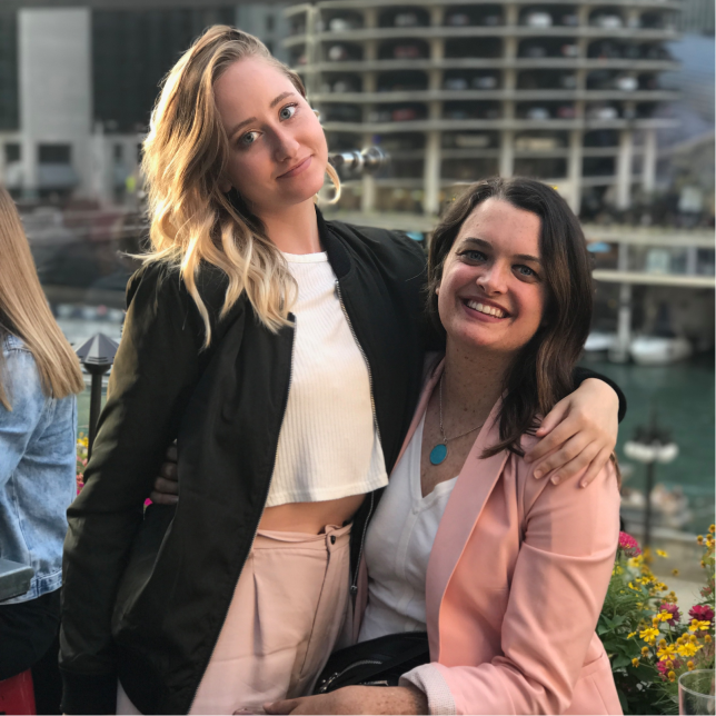 Two women smiling at the camera while sitting outside in downtown Chicago