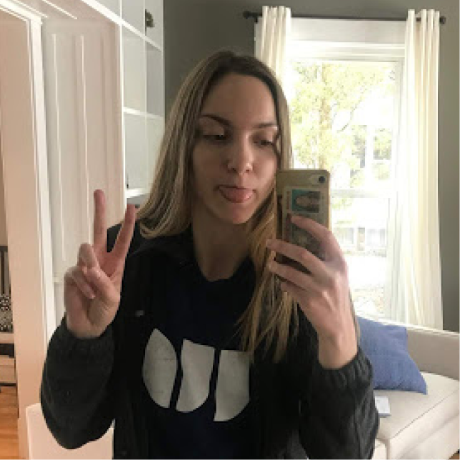 A woman taking a mirror selfie with her tongue out and holding up a peace sign