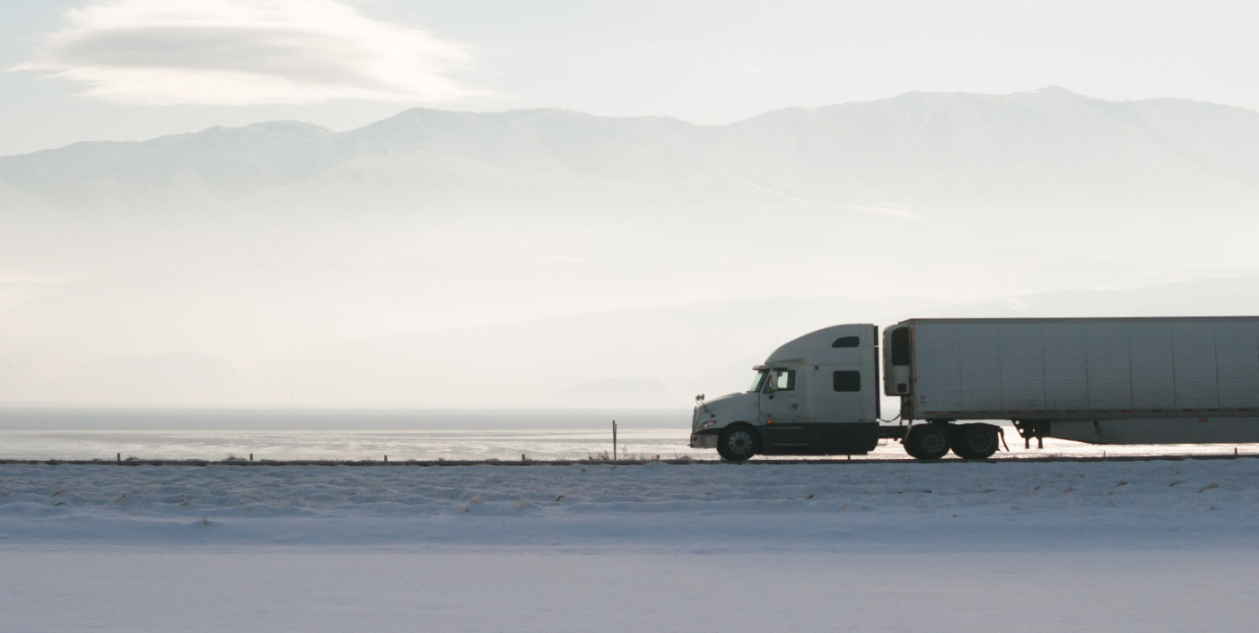 a semi truck driving along a highway next to mountains