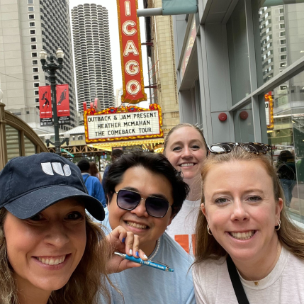 Selfie of four people in front of the Chicago Theater. One of them is holding a blue pen