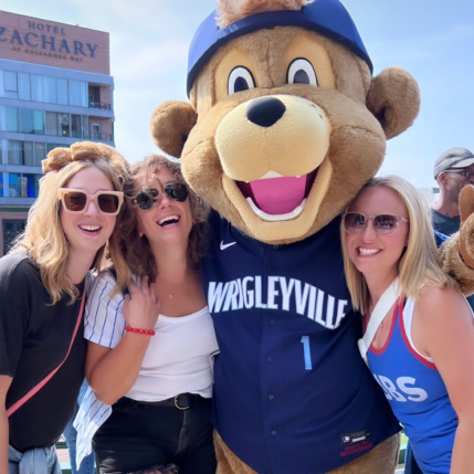 Three people taking a photo with the Cubs mascot