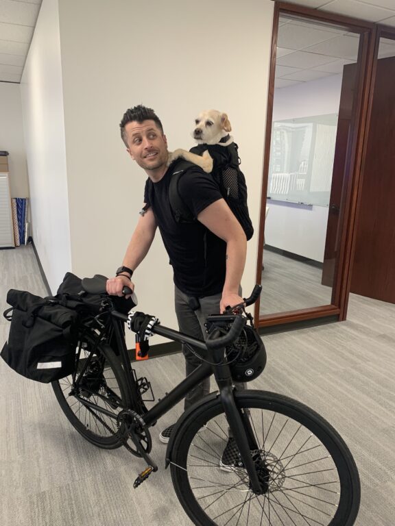 A Walker Sands Seattle team memember standing next to a bike with a dog on their back