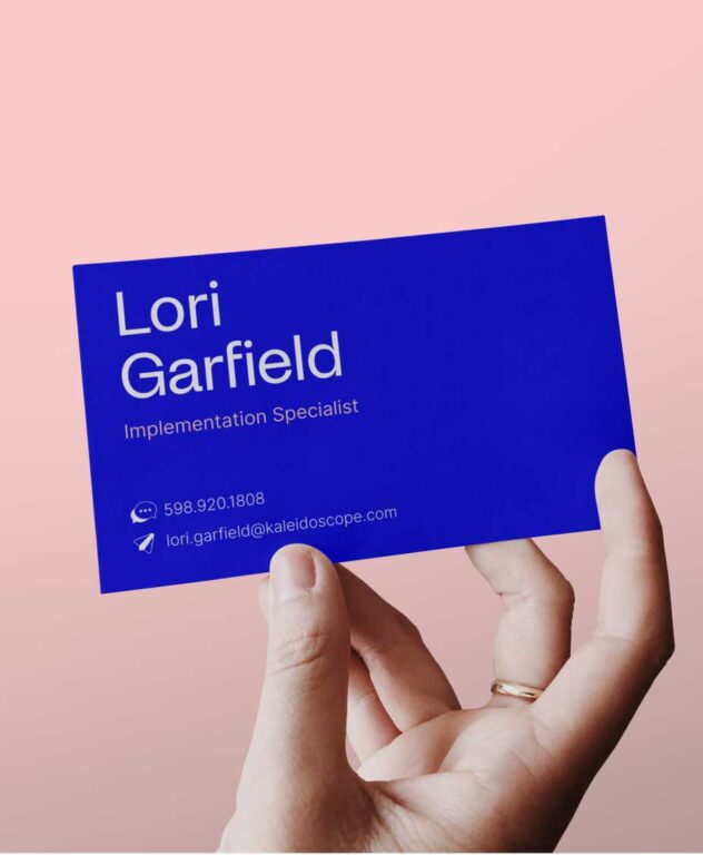 a hand holding a blue Kaleidoscope business card for "Lori Garfield, Implementation Specialist" with updated branding