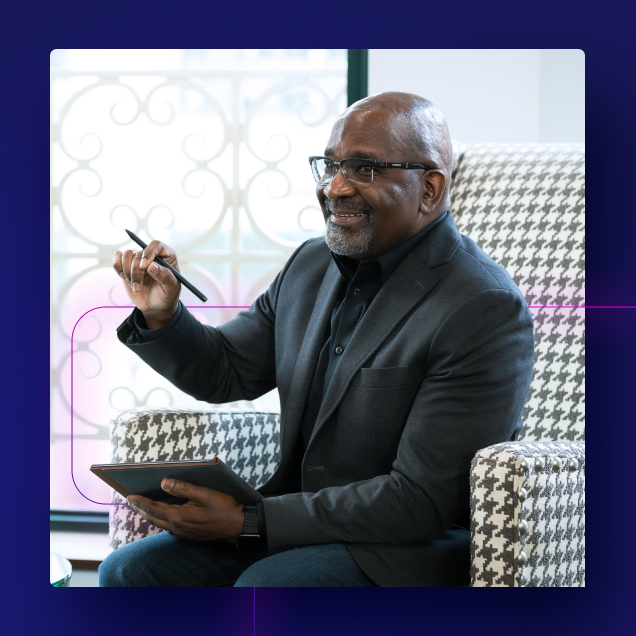 Man in a grey sports coat sitting with a tablet and a stylist pen