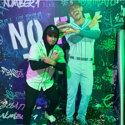 Person wearing a Seattle Mariners hat posing in front of a cardboard cut out of a Seattle Mariners player