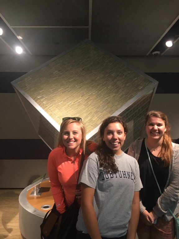 Photo of 3 people in front of a cube of money