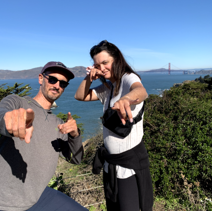 A man and woman posing in front of the Golden Gate bridge. 