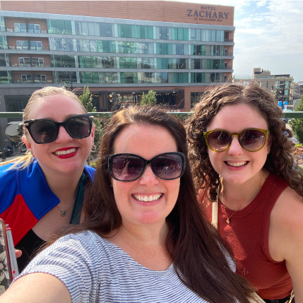Three women in sunglasses smiling taking a selfie. 
