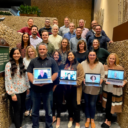 A group of poeple standing on steps. The front row is holding laptops. 