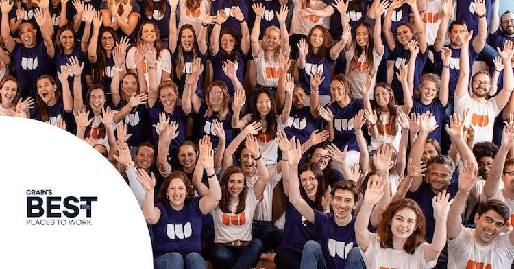 Portrait of Walker Sands Chicago employees wearing Walker Sands t-shirts and raising their hands up