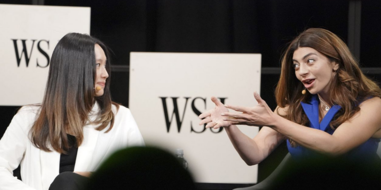 Two women on a stage, speaking in front of a Wall Street Journal logo