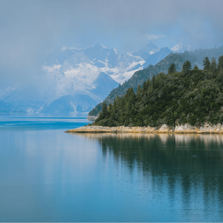 scenic view of mountains, green trees and calm, blue water