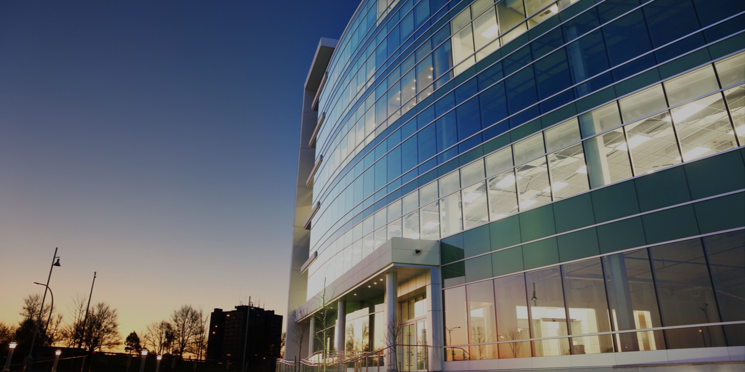 exterior shot of a modern glass office building at dusk
