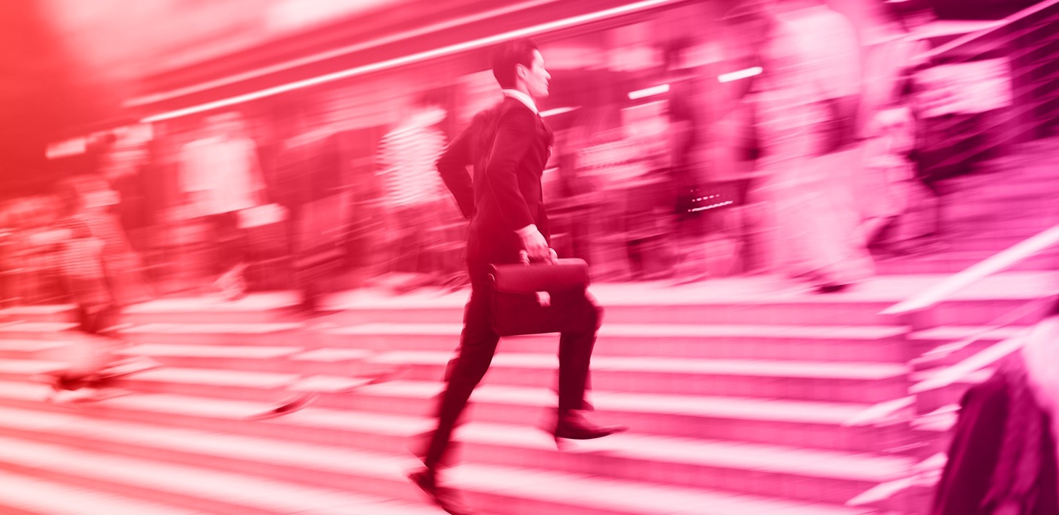 A blurry photo with a red filter of a man in a suit with a briefcase running up steps