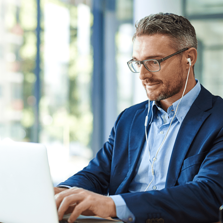 A man wearing earbuds working on a laptop