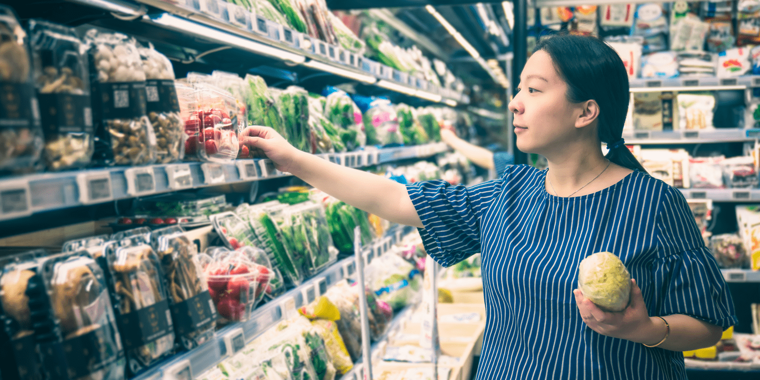 a woman with a ponytail picking out produce in a grocery store