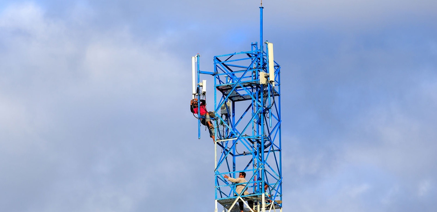 Two engineers working cell tower high in the sky