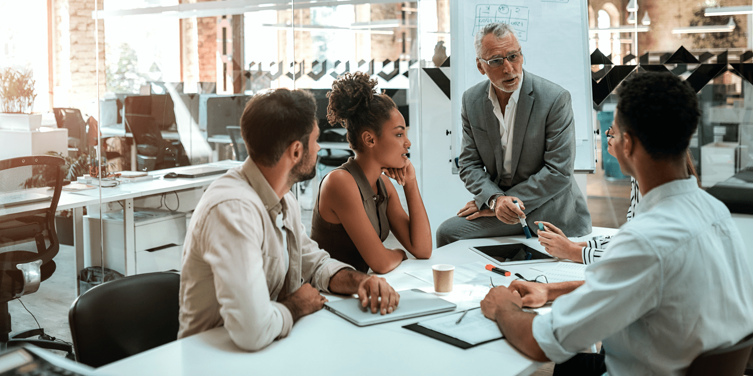 four people in conversation around a table at an office