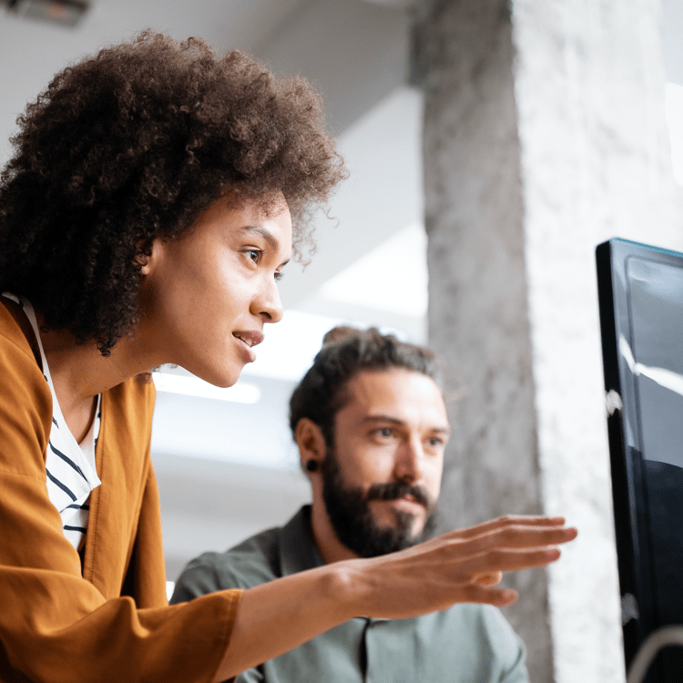 a man and a woman looking at a computer monitor together while the woman gestures